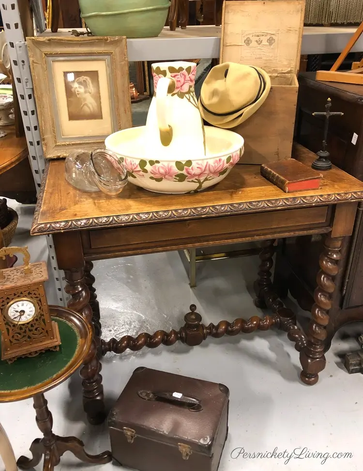 items in a brocante store: wood table with twisted legs, photo in a frame, wash basin, etc.