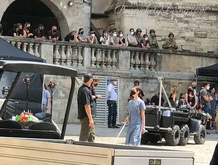 Aria Mia Loberti in blue dress and face mask rehearses walking across the square with her cane in all the light we cannot see