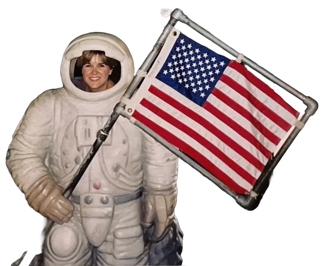 Kit in astronaut suit holding US flag
