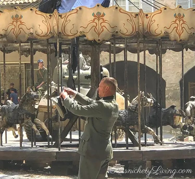 Nazi character taking a photo in front of burned carousel all the light we cannot see