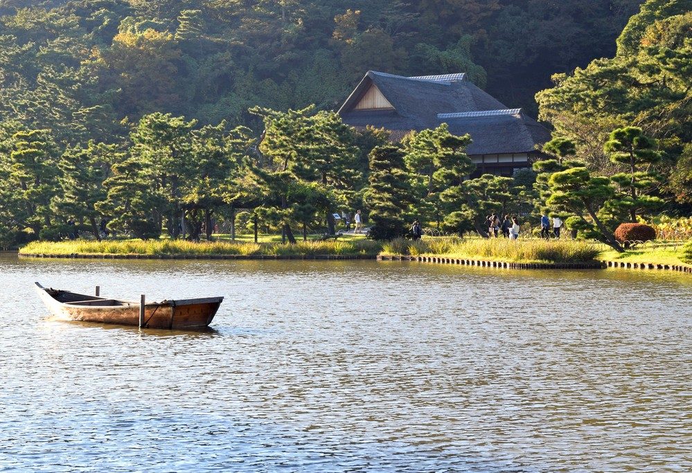Sankeien Garden pond with row boat and old japanese buildings