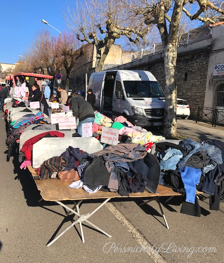 tables full of second-hand clothing at a weekly market