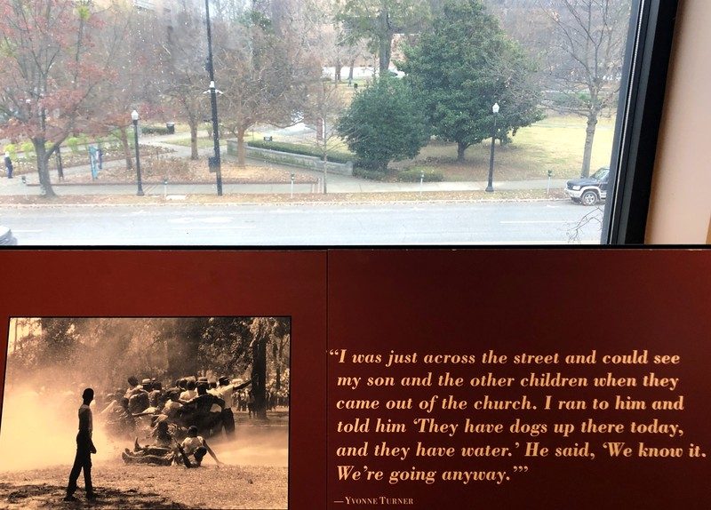 view of kelly ingram park from civil rights institute and photo of children being blasted with high power water hoses